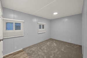 Empty room with a decorative wall, wood finished floors, and carpet floors