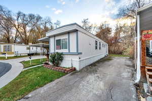 View of side of property featuring a yard and concrete driveway