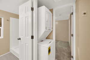 Laundry room with stacked washer / drying machine and light carpet