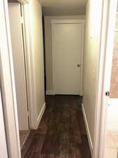 Hall with dark wood-style floors and baseboards