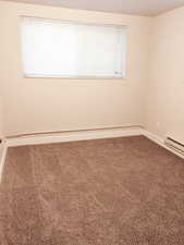 Unfurnished room featuring carpet and baseboard heating
