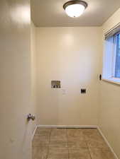 Washroom featuring light tile patterned floors, hookup for an electric dryer, and washer hookup