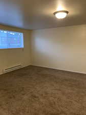 Carpeted empty room with baseboard heating and baseboards