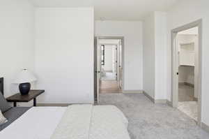 Bedroom featuring light colored carpet and a walk in closet