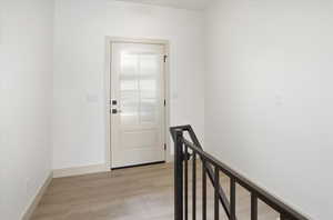 Hall with an upstairs landing and light wood-style floors