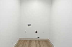 Laundry area with light wood-style floors, hookup for a washing machine, and electric dryer hookup