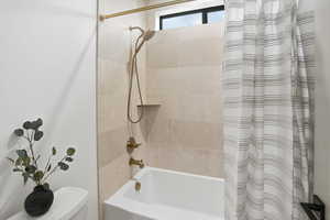 Bathroom with shower / bath combination with curtain and toilet