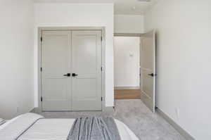 Carpeted bedroom with a closet and baseboards