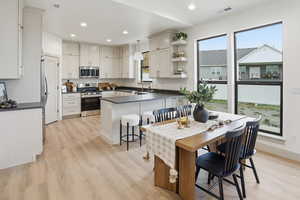 Kitchen featuring appliances with stainless steel finishes, recessed lighting, light wood-style floors, dark countertops, and open shelves