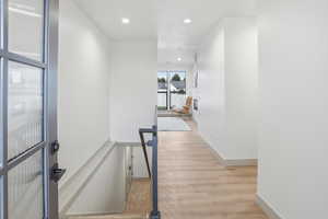 Hall with recessed lighting, light wood-style floors, and an upstairs landing