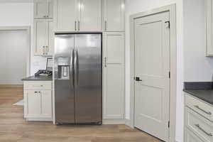 Kitchen with stainless steel fridge with ice dispenser, white cabinetry, and light wood finished floors