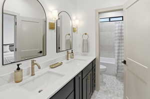 Bathroom featuring double vanity and shower / tub combo with curtain