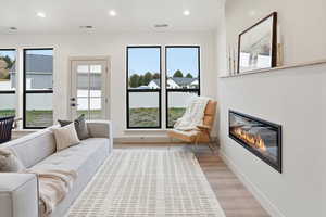 Living area featuring a glass covered fireplace, recessed lighting, and wood finished floors
