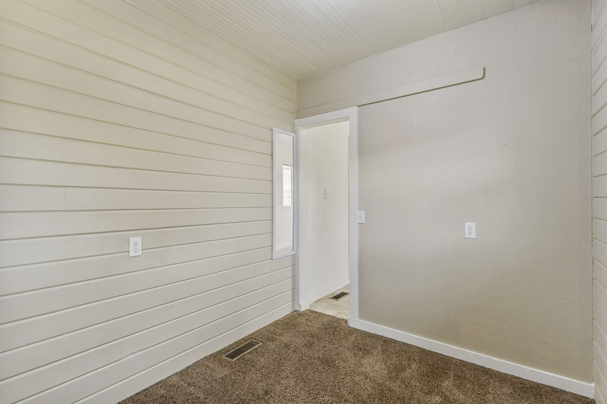 Empty room with carpet flooring and wood walls
