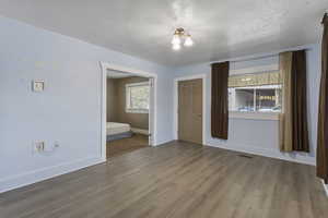 Unfurnished bedroom with wood finished floors and a textured ceiling