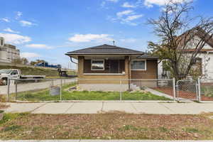 Bungalow-style home featuring a gate, a fenced front yard, covered porch, and brick siding
