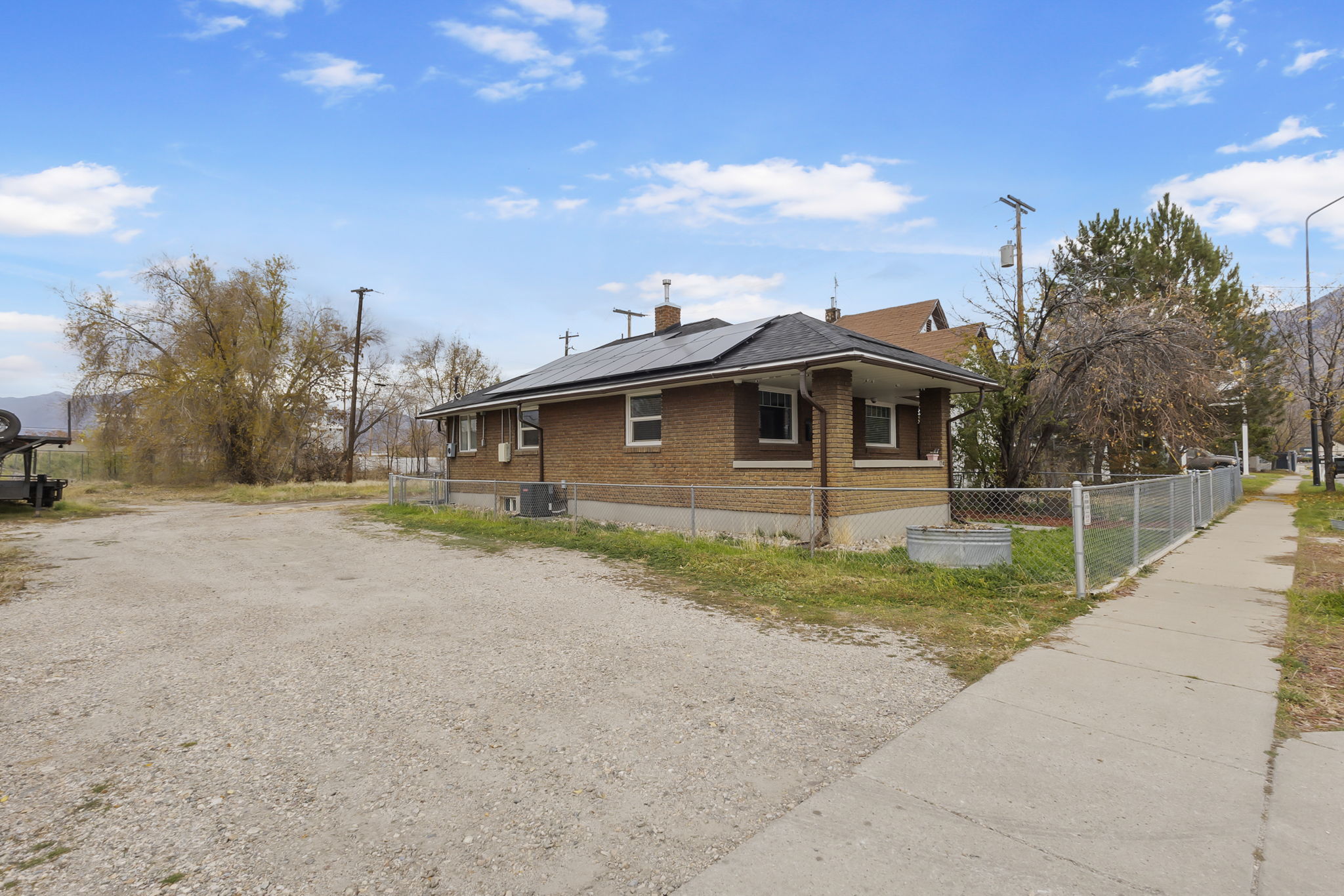 View of side of property featuring solar panels, brick siding, a chimney, and driveway