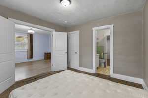 Unfurnished bedroom featuring light carpet, a textured ceiling, and ensuite bathroom