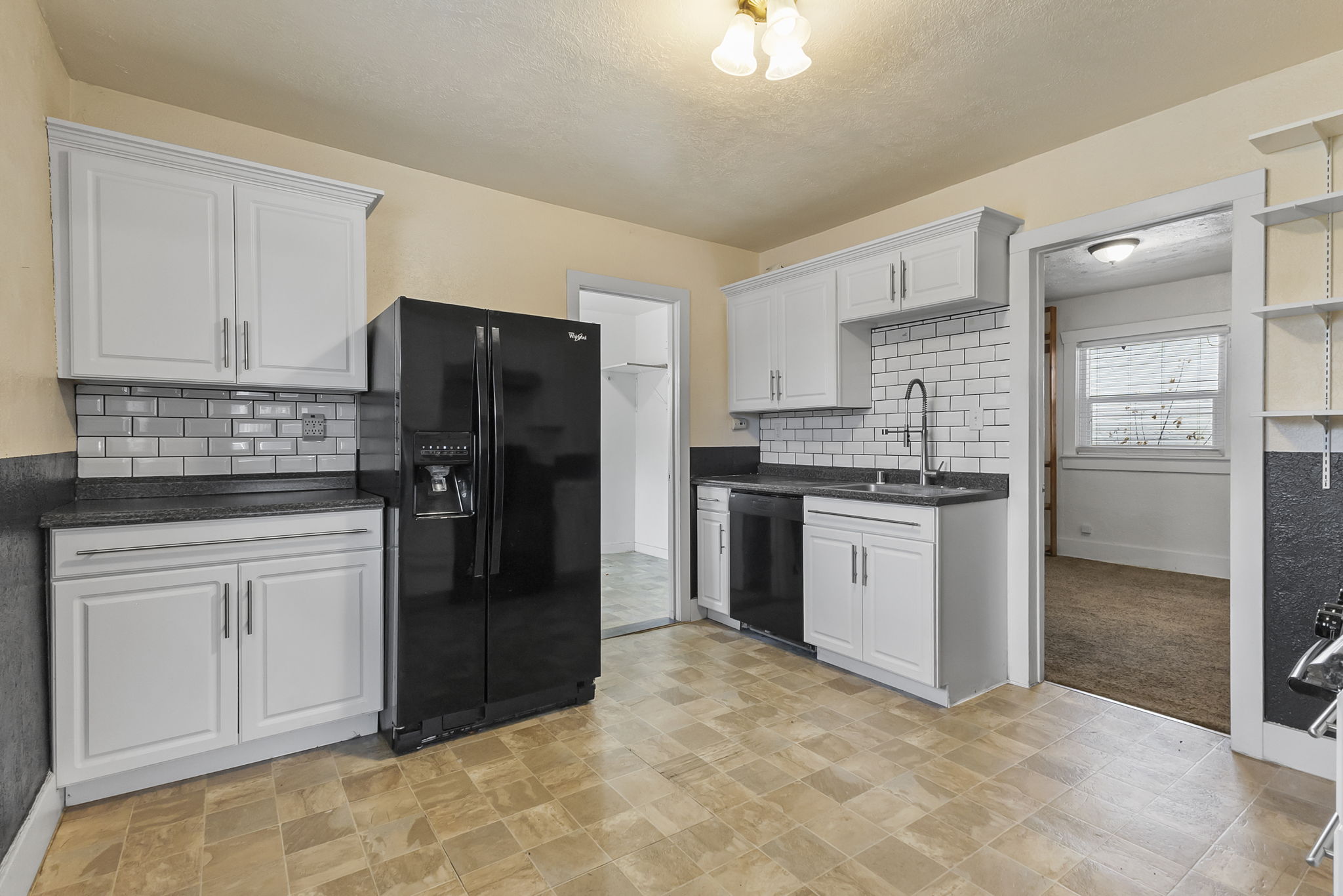 Kitchen with black appliances, white cabinets, tasteful backsplash, and dark stone countertops