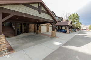 View of property exterior featuring stone siding, driveway, a garage, and stairs