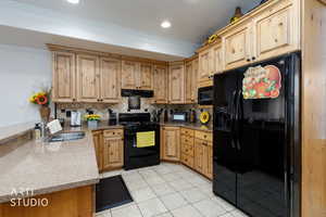 Kitchen featuring black appliances, tasteful backsplash, light tile patterned floors, granite countertops, and ornamental molding