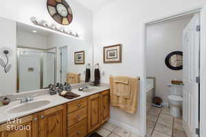Bathroom with light tile patterned floors, double vanity, and a stall shower