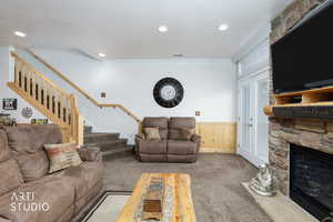 Living room with carpet floors, crown molding, stairs, wainscoting, and a fireplace