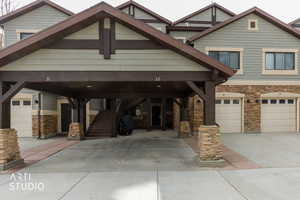 Craftsman-style house featuring stone siding, concrete driveway, stairway, and a carport