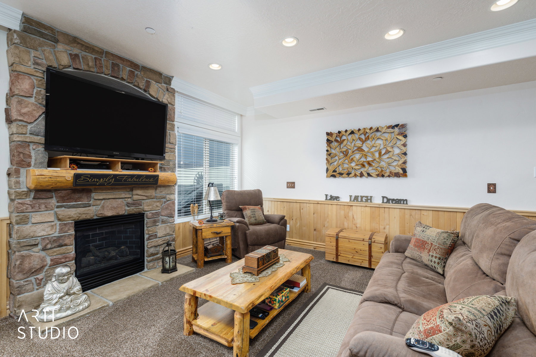 Carpeted living area featuring a wainscoted wall, ornamental molding, wood walls, recessed lighting, and a fireplace