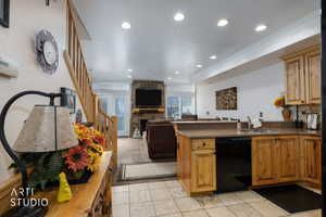 Kitchen featuring a peninsula, black dishwasher, a stone fireplace, open floor plan, and recessed lighting
