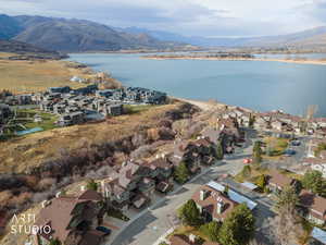 Aerial view of property and surrounding area featuring nearby suburban area and a water and mountain view