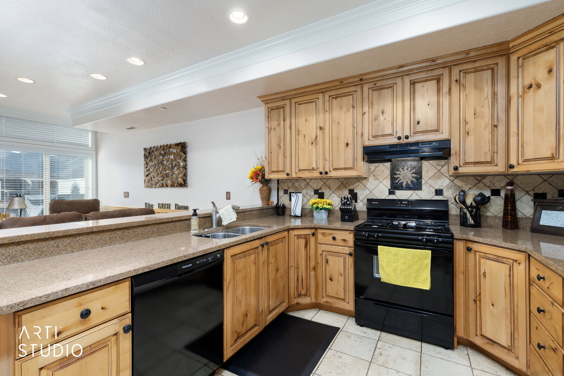 Kitchen featuring black appliances, granite counters, crown molding, under cabinet range hood, and open floor plan