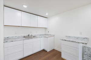 Kitchen with dark wood-style flooring, white cabinets, and recessed lighting