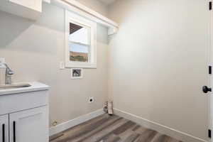 Washroom with dark wood-type flooring, washer hookup, cabinet space, and electric dryer hookup