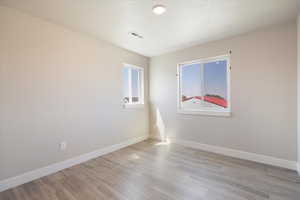 Empty room featuring light wood-style floors and a textured ceiling