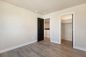 Unfurnished bedroom featuring a spacious closet and light wood-style flooring