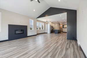 Unfurnished living room with light wood-style floors, recessed lighting, high vaulted ceiling, and a chandelier
