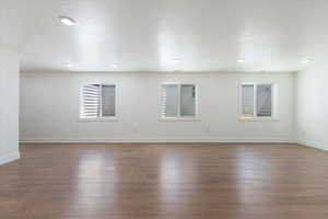Empty room with healthy amount of natural light, dark wood-type flooring, and a textured ceiling