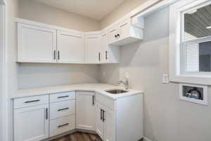 Laundry room featuring hookup for a washing machine, dark wood-style flooring, and cabinet space