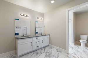 Bathroom featuring double vanity and light marble finish floors