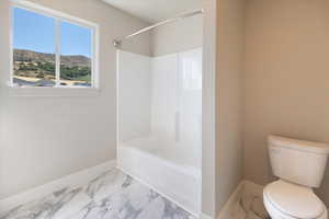 Full bathroom with marble finish floors, washtub / shower combination, and a mountain view