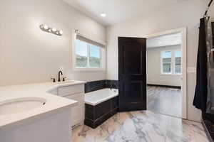 Full bathroom featuring vanity, a bath, light marble finish floors, and recessed lighting