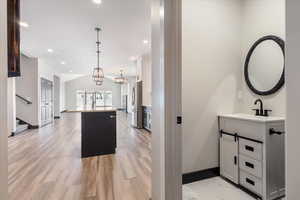 Kitchen with a kitchen island with sink, white cabinetry, pendant lighting, freestanding refrigerator, and vaulted ceiling