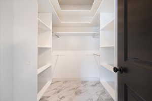 Spacious closet featuring light marble finish floors