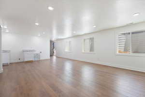 Unfurnished living room with dark wood-type flooring, recessed lighting, and a textured ceiling