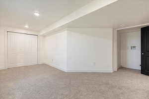Additional living space featuring light colored carpet and recessed lighting