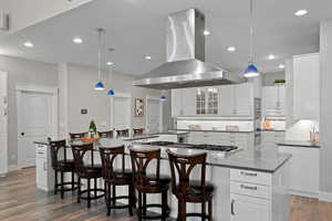 Kitchen with white cabinetry, glass insert cabinets, island range hood, dark wood-type flooring, and recessed lighting