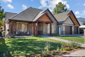 Craftsman inspired home with stone siding, a shingled roof, stucco siding.