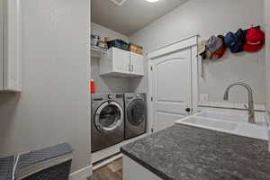 Basement Washroom with a textured wall, separate washer and dryer, dark wood-style flooring, and cabinet space