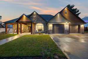 View of front of property with stone siding, concrete driveway, a yard, and an attached garage